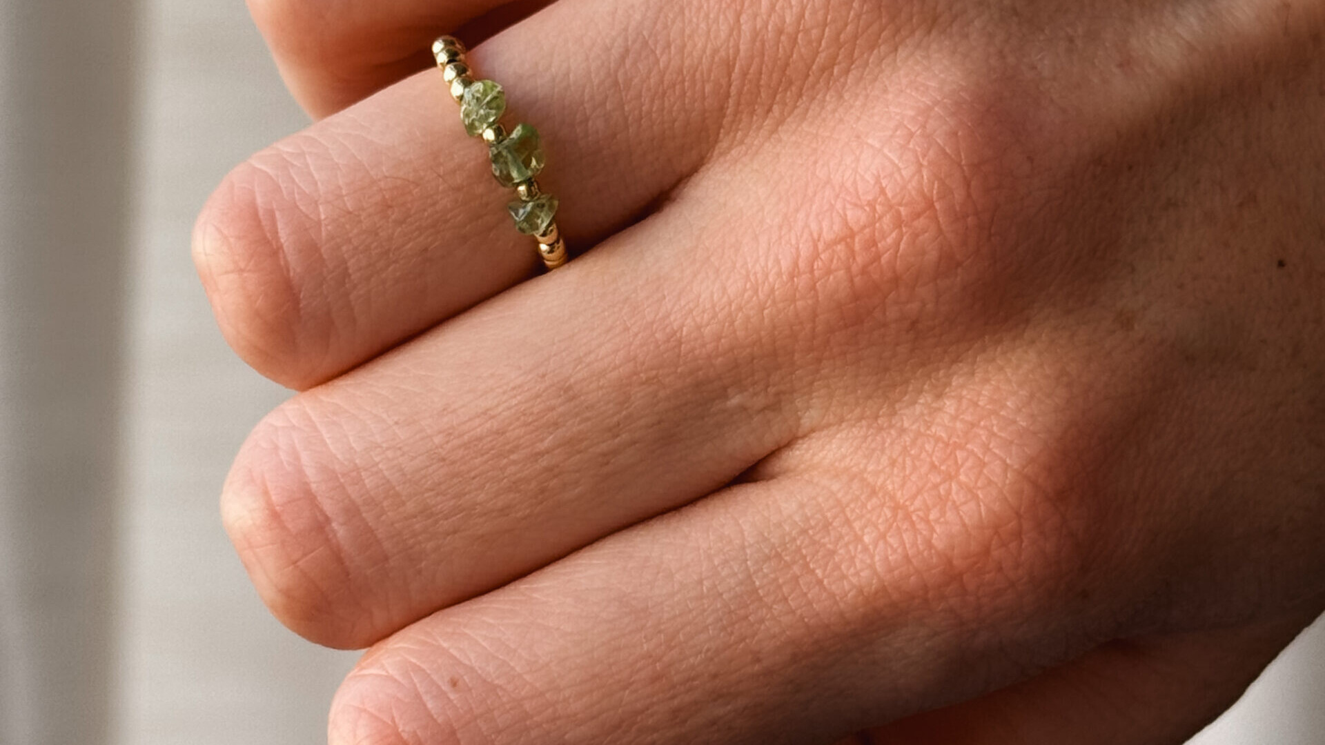 Nahaufnahme Perlenring in Gold mit Peridot Edelsteinen